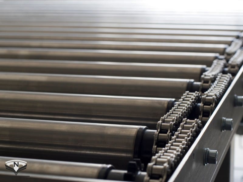 Với băng tải con lăn truyền động xích khoảng cách con lăn còn phụ thuộc vào bước xích