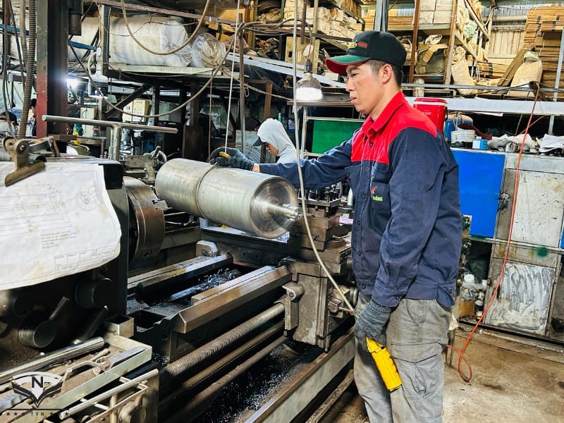 Kỹ thuật viên đang gia công rulo băng tải trên máy tiện